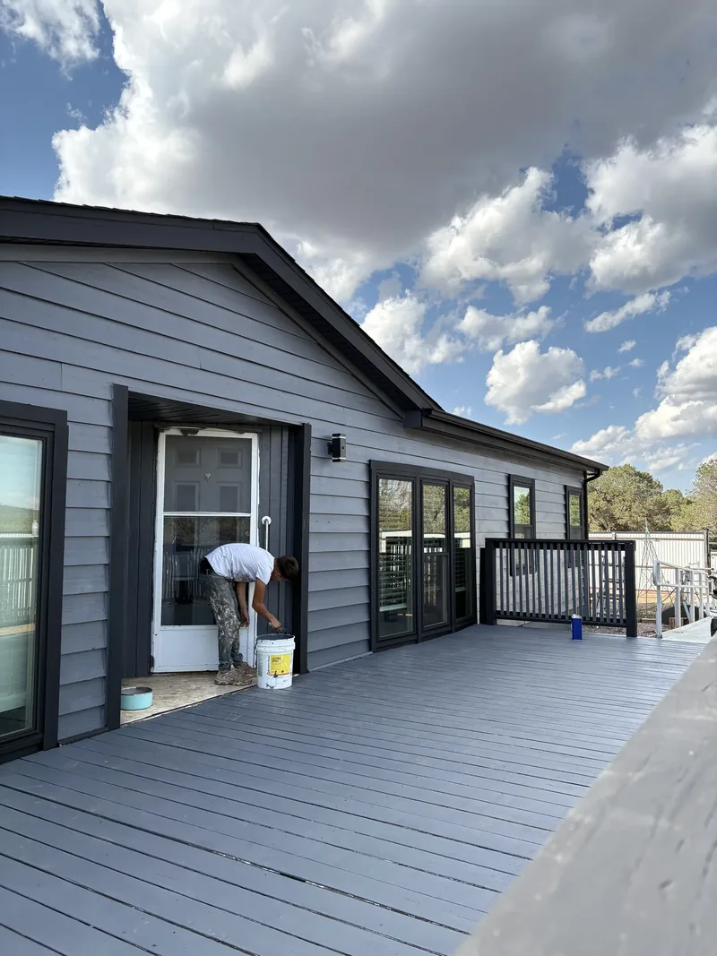 Gray composite deck cleaned and re-coated under a dramatic sky